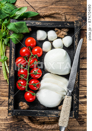 Mozzarella cheese, basil and tomato cherry in wooden tray, Caprese salad. wooden background. Top view Mozzarella cheese, basil and tomato cherry in wooden tray, Caprese salad. wooden background. Top view 87470490