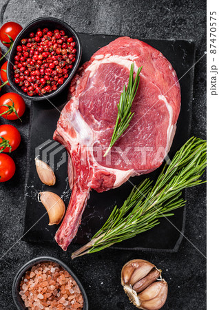 Cooking Raw Rib eye or Tomahawk beef steak with spices. Black background. Top view 87470575