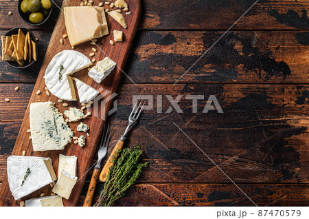 Cheese plate with camembert, brie, Gorgonzola, parmesan, olives, nuts and crackers. Wooden background. Top view. Copy space Cheese plate with camembert, brie, Gorgonzola, parmesan, olives, nuts and crackers. Wooden background. Top view. Copy space 87470579