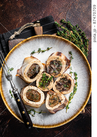 Baked marrow veal beef bones in plate with thyme and herbs. Dark background. Top view Baked marrow veal beef bones in plate with thyme and herbs. Dark background. Top view 87470709