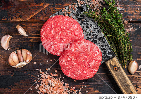 Raw steak cutlets with mince beef meat on a butcher cleaver. Wooden background. Top view Raw steak cutlets with mince beef meat on a butcher cleaver. Wooden background. Top view 87470907