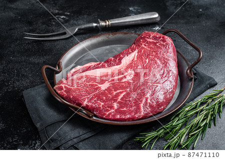 Raw top sirloin beef meat steak in a steel tray with rosemary. Black background. Top view Raw top sirloin beef meat steak in a steel tray with rosemary. Black background. Top view 87471110