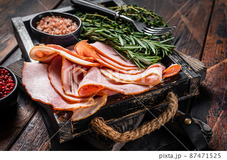 Italian Prosciutto cotto Ham slices in wooden tray with thyme and rosemary. Wooden background. Top view Italian Prosciutto cotto Ham slices in wooden tray with thyme and rosemary. Wooden background. Top view 87471525