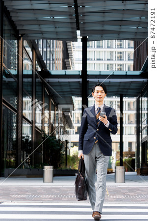 オフィス街でスマートフォンを使うビジネスマン 87472191