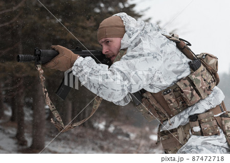 Soldier in winter camouflaged uniform in Modern warfare army on a snow day on forest battlefield with a rifle. Model face very similar to Ukraine prime minister. 87472718