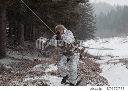 Soldier in winter camouflaged uniform in Modern warfare army on a snow day on forest battlefield with a rifle. Model face very similar to Ukraine prime minister. 87472723