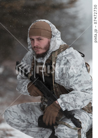 Soldier in winter camouflaged uniform in Modern warfare army on a snow day on forest battlefield with a rifle. Model face very similar to Ukraine prime minister. 87472730