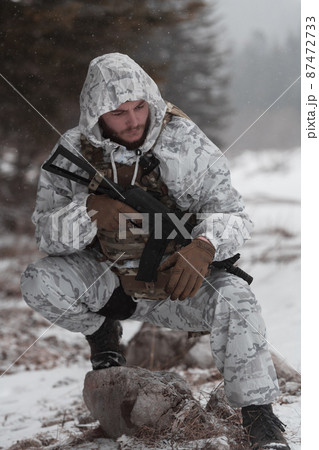 Soldier in winter camouflaged uniform in Modern warfare army on a snow day on forest battlefield with a rifle. Model face very similar to Ukraine prime minister. 87472733