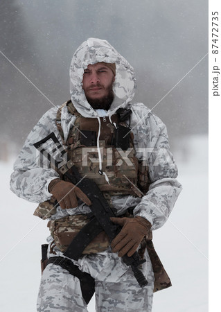 Soldier in winter camouflaged uniform in Modern warfare army on a snow day on forest battlefield with a rifle. Model face very similar to Ukraine prime minister. 87472735