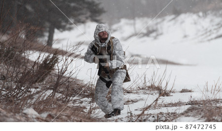 Soldier in winter camouflaged uniform in Modern warfare army on a snow day on forest battlefield with a rifle. Model face very similar to Ukraine prime minister. 87472745