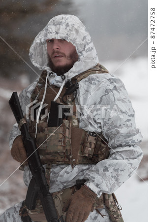 Soldier in winter camouflaged uniform in Modern warfare army on a snow day on forest battlefield with a rifle. Model face very similar to Ukraine prime minister. 87472758