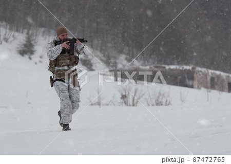 Soldier in winter camouflaged uniform in Modern warfare army on a snow day on forest battlefield with a rifle. Model face very similar to Ukraine prime minister. 87472765