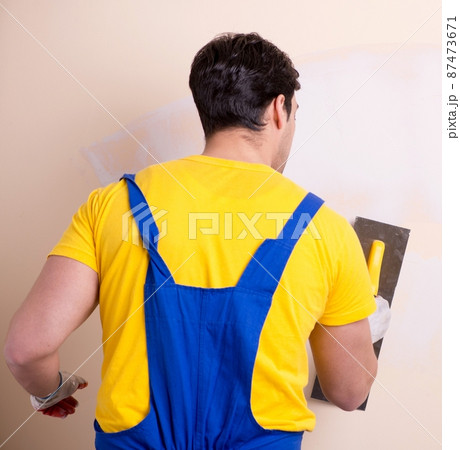 Young contractor employee applying plaster on wall 87473671