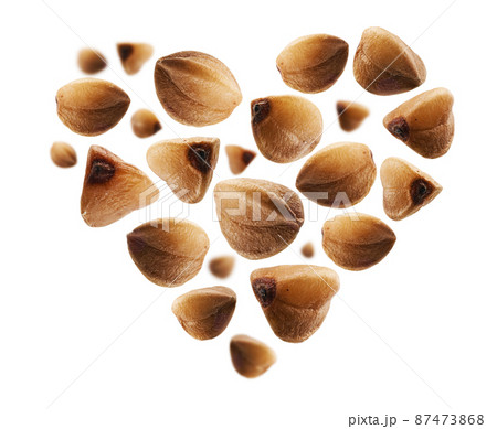 Ripe buckwheat grains in the shape of a heart on a white background 87473868