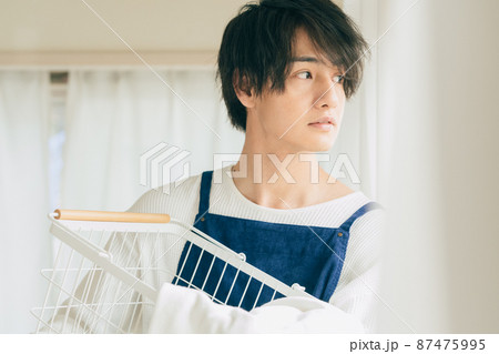 洗濯物を片付ける若い男性 87475995