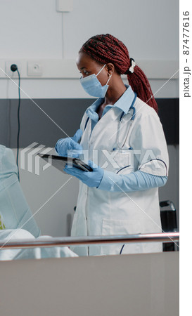 Woman working as doctor with tablet consulting ill patient Woman working as doctor with tablet consulting ill patient 87477616