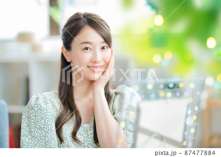 リビングで鏡を見ながら肌を気にする笑顔の若い女性 87477884