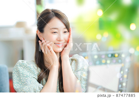 リビングで鏡を見ながら肌を気にする笑顔の若い女性 87477885