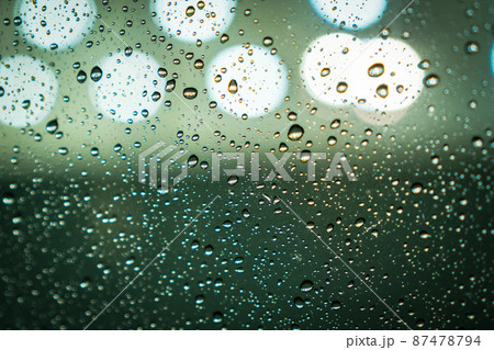 Rain drops on window glass with bokeh lights on the background. Soft focus. Dark blue green abstract wallpaper or backdrop for web design Rain drops on window glass with bokeh lights on the background. Soft focus. Dark blue green abstract wallpaper or backdrop for web design 87478794