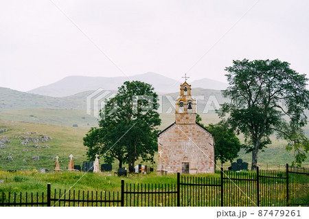 Cemetery next to a small old brick church on a green meadow Cemetery next to a small old brick church on a green meadow 87479261