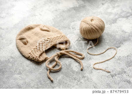Baby knitted beige clothes on a white concrete background 87479453