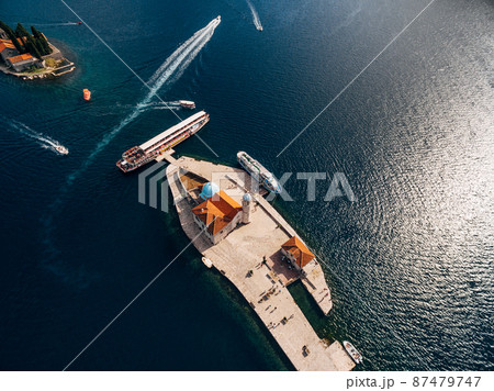 Boats moored near the island of Gospa od Skrpjela on the background of St. George island. Top view 87479747