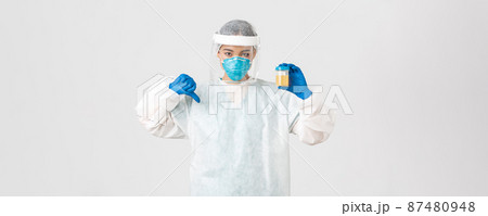 Covid-19, coronavirus disease, healthcare workers concept. Side view of serious tech lab employee, researcher in personal protective equipment show thumb-down in disapproval, bad analyze result Covid-19, coronavirus disease, healthcare workers concept. Side view of serious tech lab employee, researcher in personal protective equipment show thumb-down in disapproval, bad analyze result 87480948