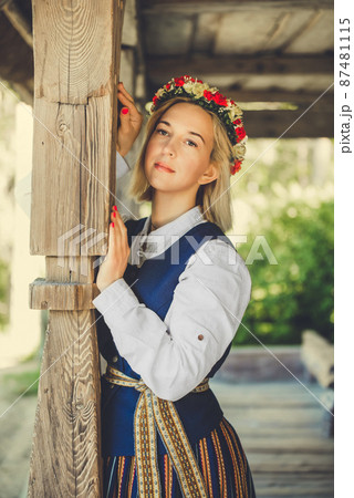 Latvian woman in traditional clothing posing on nature in village. 87481115