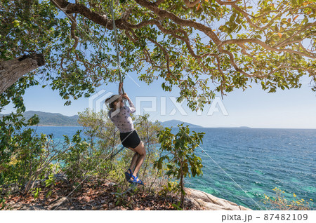 Young woman hanging rope with tree in tropical sea Young woman hanging rope with tree in tropical sea 87482109