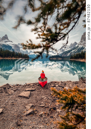 Female traveler in winter coat sitting on canoe in Spirit Island on Maligne Lake at Jasper national park 87482130