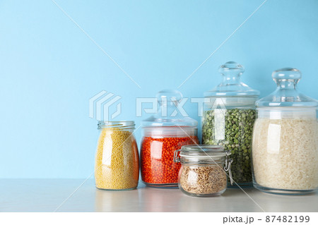 Glass jars with different types of groats on white wooden table 87482199