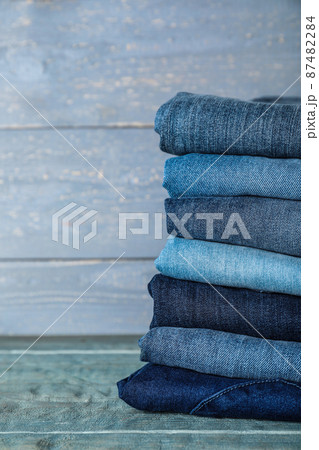 Stack of different jeans on blue wooden table. Space for text 87482284