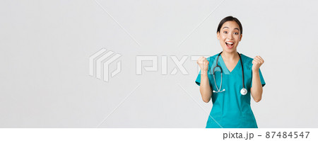 Covid-19, healthcare workers and preventing virus concept. Hopeful and relieved, joyful asian pretty female doctor, physician rejoicing with fists pump, congrats or praise someone, winning 87484547