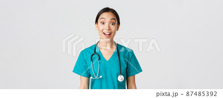 Healthcare workers, preventing virus, quarantine campaign concept. Happy and excited asian female doctor, physician in scrubs look amazed, hear awesome news, white background Healthcare workers, preventing virus, quarantine campaign concept. Happy and excited asian female doctor, physician in scrubs look amazed, hear awesome news, white background 87485392
