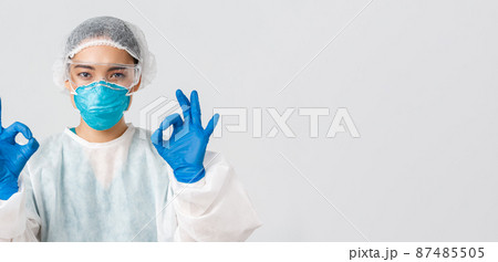 Covid-19, coronavirus disease, healthcare workers concept. Close-up of pleased serious-looking asian female in personal protective equipment show okay gesture, approve or guarantee something 87485505