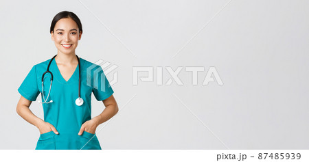 Covid-19, healthcare workers, pandemic concept. Confident smiling pretty asian female doctor, physician looking determined and upbeat, holding hands in pockets of scrubs, examine patients in clinic Covid-19, healthcare workers, pandemic concept. Confident smiling pretty asian female doctor, physician looking determined and upbeat, holding hands in pockets of scrubs, examine patients in clinic 87485939
