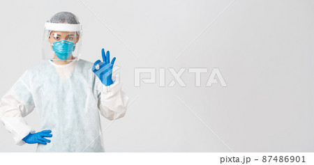 Covid-19, coronavirus disease, healthcare workers concept. Serious-looking professional female asian doctor in personal protective equipment, showing okay gesture, ensure safety of patient 87486901