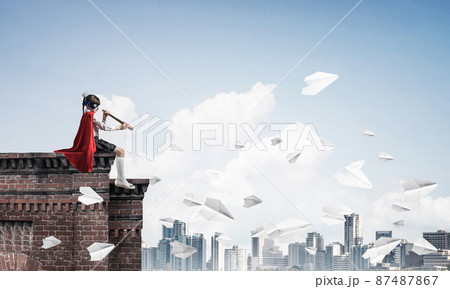 Girl power concept with cute kid guardian against cityscape background. Mixed media 87487867