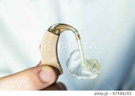 肌色の補聴器を持つ男性の手 87488165