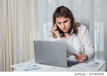 Disabled woman talks on phone looking at project paper Disabled woman talks on phone looking at project paper 87489090
