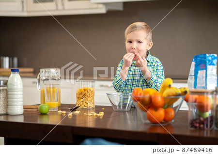 Hungry kid putting some food in his mouth 87489416