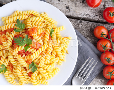 Pasta fusilli with tomatoes with parsley on a old rustic gray wooden background Pasta fusilli with tomatoes with parsley on a old rustic gray wooden background 87489723