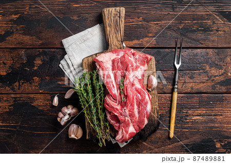 Raw Boneless lamb meat, raw neck meat on wooden board. Black background. Top view 87489881