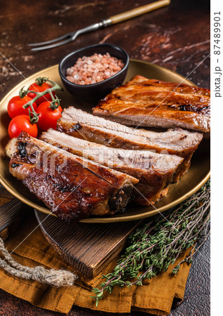 Chopped BBQ pork ribs on a plate with herbs. Dark background. Top view Chopped BBQ pork ribs on a plate with herbs. Dark background. Top view 87489901