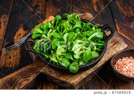 Fresh Raw green lambs lettuce Corn salad leaves in a pan. Dark wooden background. Top view 87489929