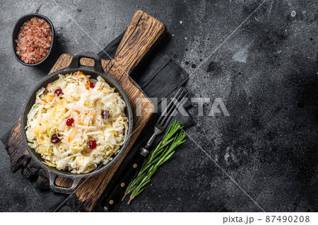Sauerkraut in a skillet with black pepper and cranberry, Fermented cabbage. Black background. Top view. Copy space 87490208