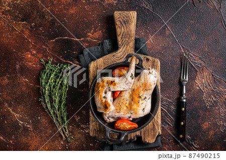 Fried rabbit legs in a pan with herbs. Dark background. Top view 87490215