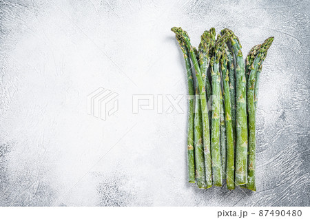 Frozen cold asparagus on a old kitchen table. White background. Top view. Copy space 87490480