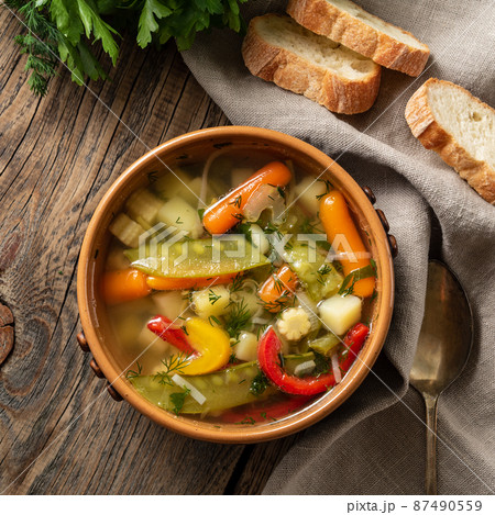 Bright spring vegetable dietary vegetarian soup. Top view, brown rustic wood background, linen napkin. Bright spring vegetable dietary vegetarian soup. Top view, brown rustic wood background, linen napkin. 87490559