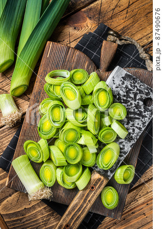 Chopped Green Leek onion with big cleaver on cutting board. Wooden background. Top view 87490676